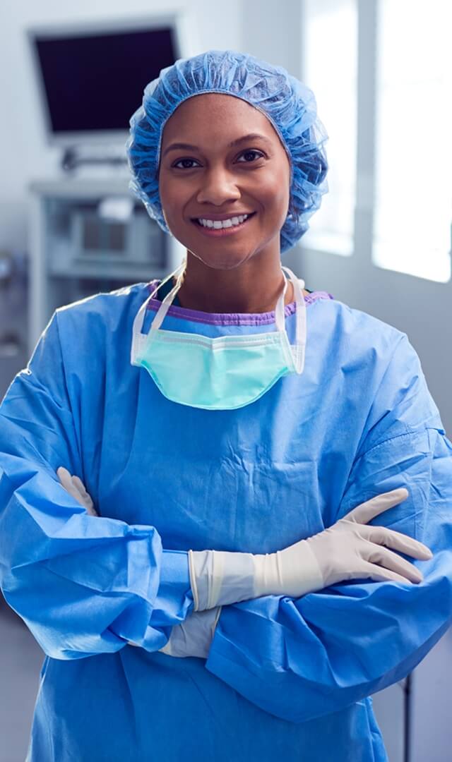A docotor is wearing blue non woven surgical gown and cap