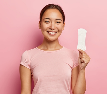 A girl in pink t-shirt holding plain white hydrophilic non woven sanitary pad in her hand